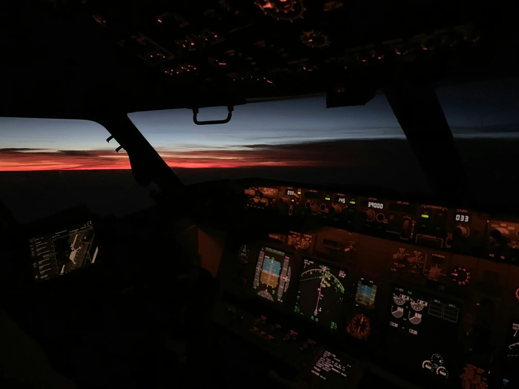 A commercial aircraft cockpit at sunset